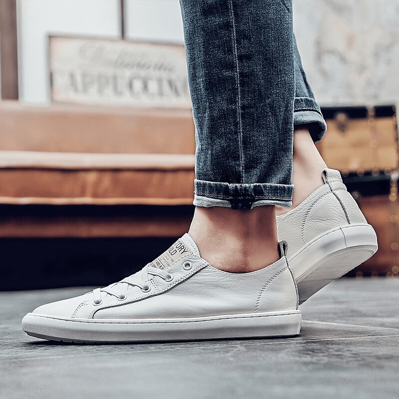 Side view of male feet wearing luxury genuine leather casual breathable shoes, slip-on design, in a stylish indoor setting.